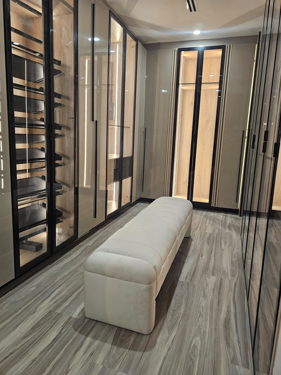 Dressing room with illuminated cabinetry and an upholstered bench